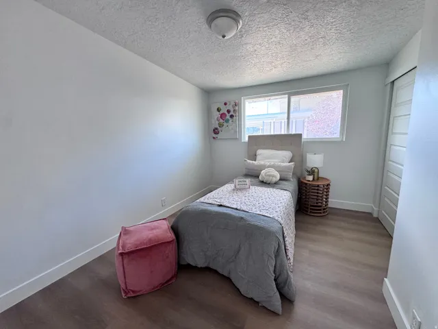 White walls, wood-finish flooring, sliding closet door, and a window for natural illumination