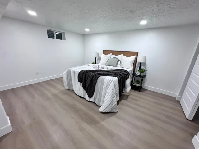 Spacious room featuring wood-finish flooring, recessed lighting, and a horizontal window with blinds