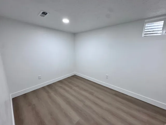 Recessed ceiling lighting, wood-finish flooring, white walls, and a window with frosted glass