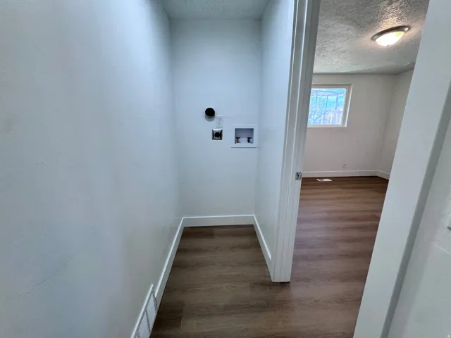 Laundry area with wood-finish flooring, white walls, and hookups
