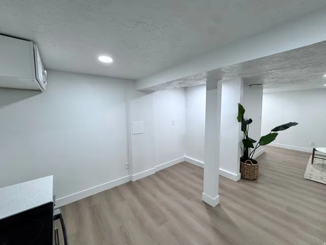 Recessed ceiling lighting, wood-finish flooring, white walls, and a built-in overhead cabinet