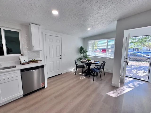 White shaker cabinetry, light wood-finish flooring, stainless steel dishwasher, white subway tile backsplash, and recessed lighting