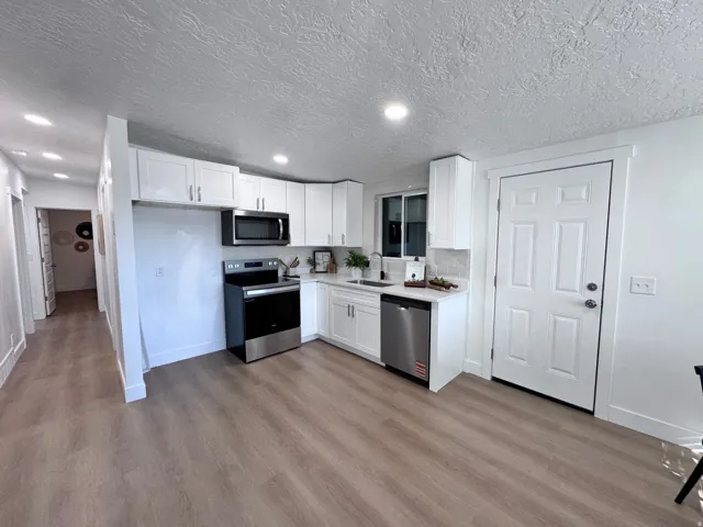 Kitchen featuring white cabinetry, stainless steel appliances, light-toned wood-finish flooring, and recessed lighting