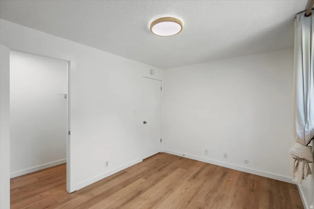 Wood-finish flooring with white walls and a contemporary flush-mount ceiling light