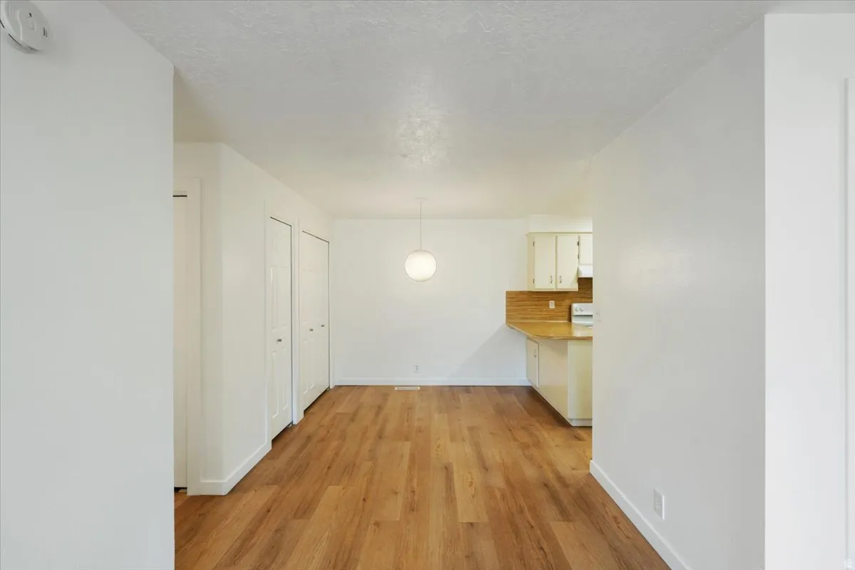 Wood-finish flooring throughout, white walls, and a contemporary spherical pendant light