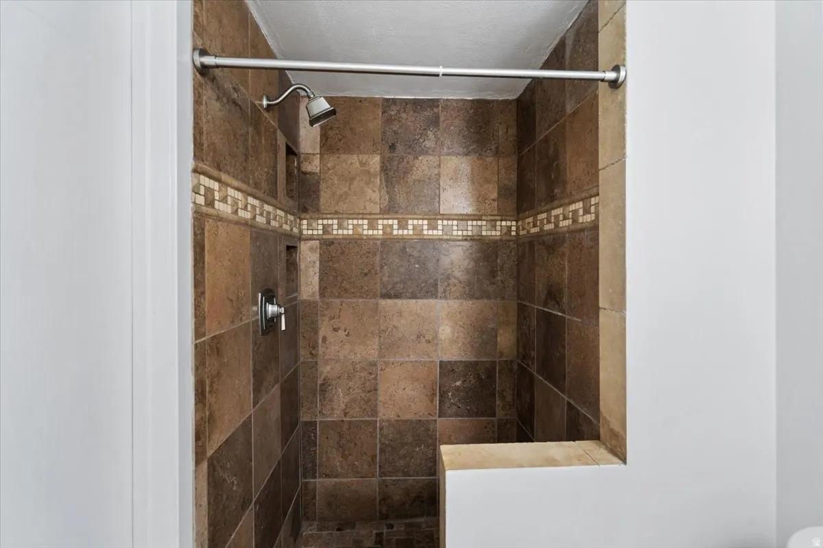 Tiled shower with a decorative mosaic accent band, recessed shelf, and built-in bench