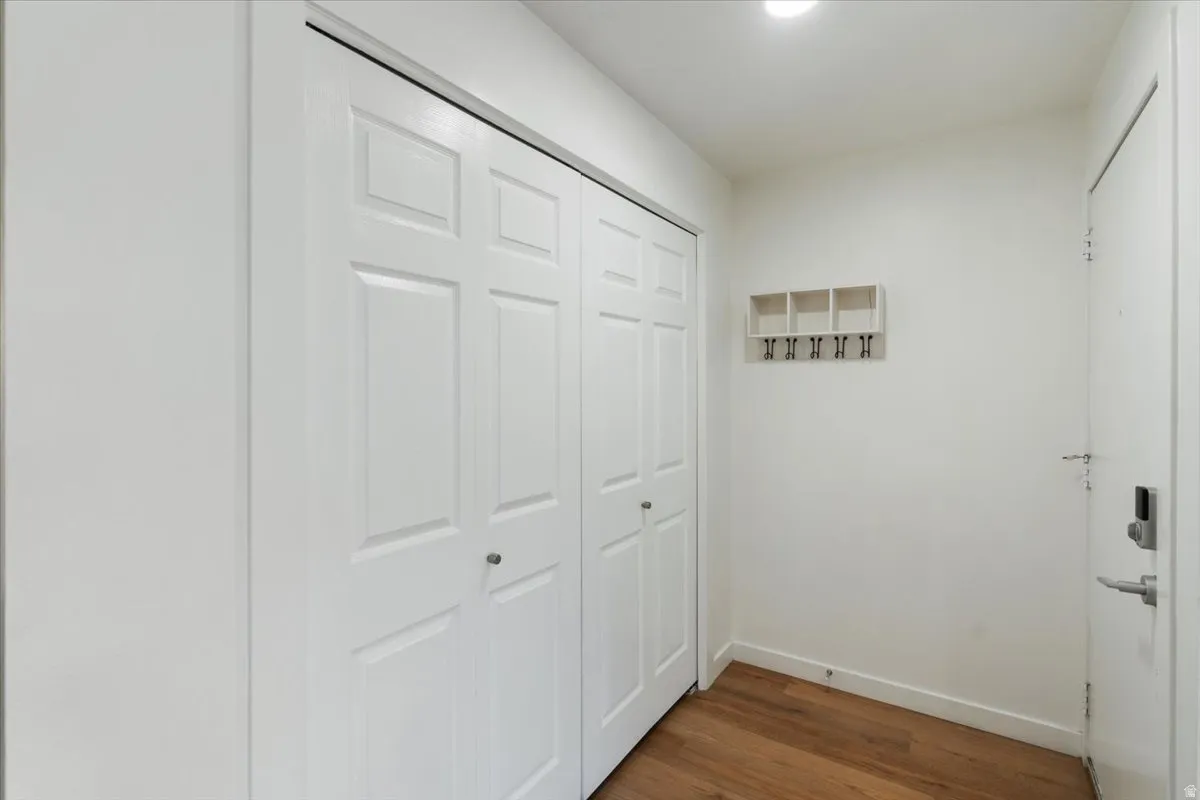 White paneled bi-fold closet doors, wood-finish flooring, recessed lighting, and a white entry door with a digital lock