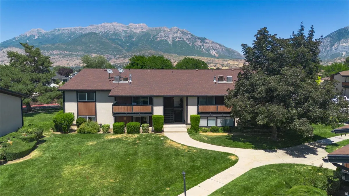 Two-story exterior with a brown shingle roof, surrounded by mature trees and manicured landscaping