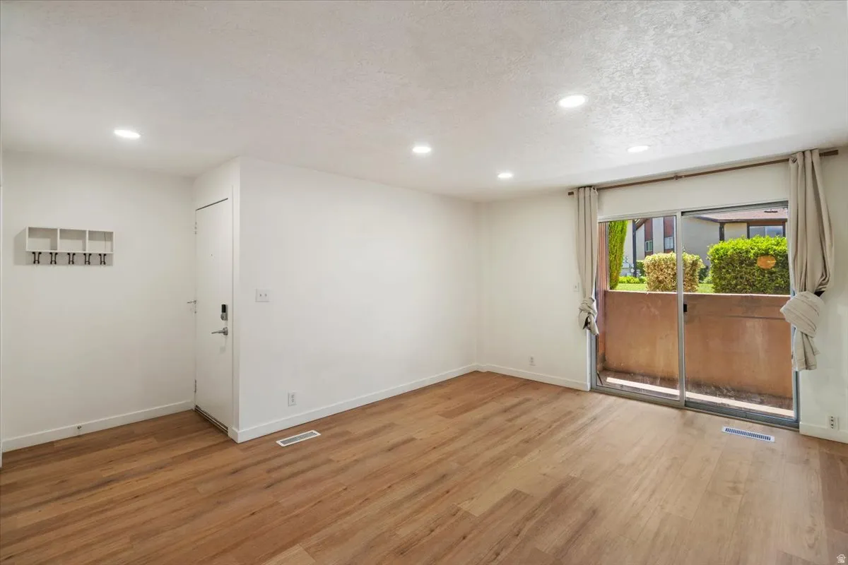 Wood-finish flooring, recessed lighting, and a sliding glass door to an outdoor patio