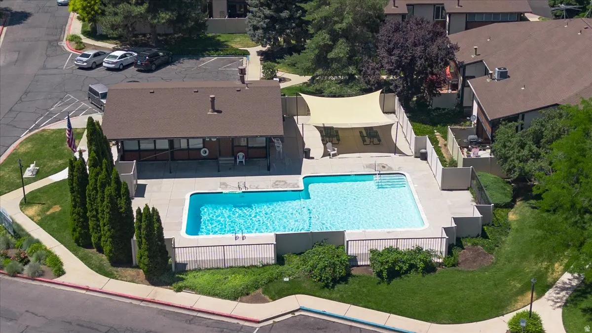 Outdoor swimming pool with concrete surround, adjacent building, and shaded patio area