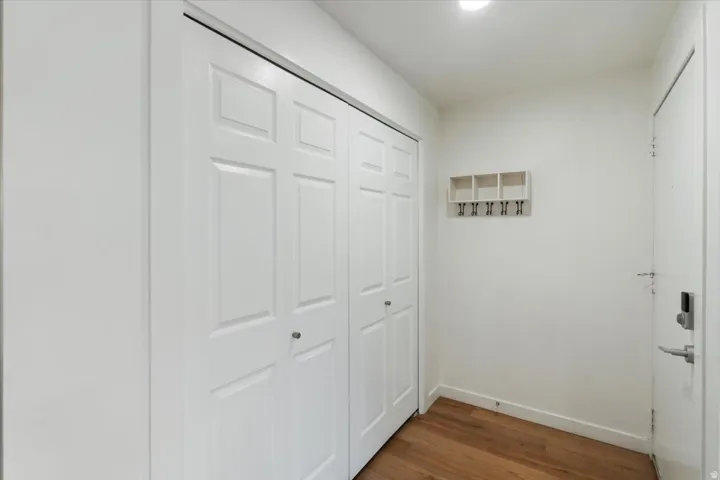 White paneled bi-fold closet doors, wood-finish flooring, recessed lighting, and a white entry door with a digital lock