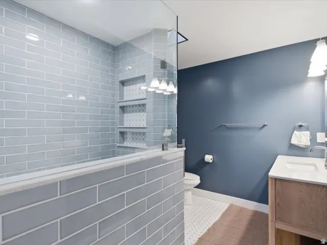 Glass-enclosed shower with subway tile surround and integrated shelving