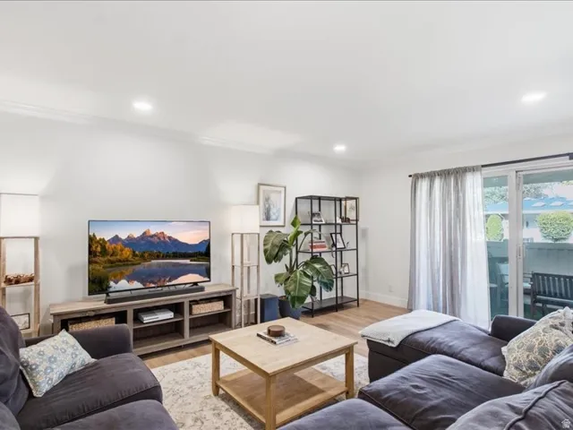Recessed ceiling lighting, wood-finish flooring, white walls, and sliding glass doors