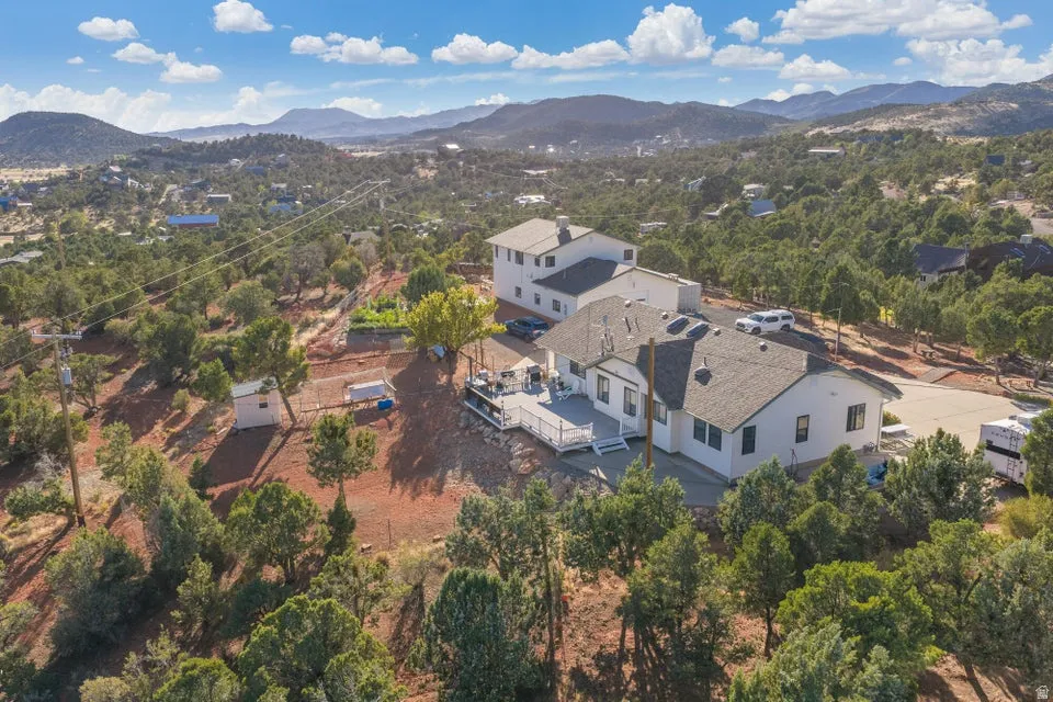 Expansive property with a multi-level deck, surrounding natural landscape, and distant mountain scenery
