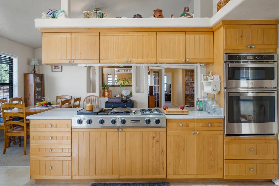 Kitchen featuring extensive light wood cabinetry, stainless steel range with gas burners, stainless steel double wall ovens, and white countertops