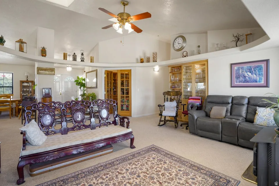 Vaulted ceilings with a ceiling fan, illuminated display ledges, and built-in cabinetry with glass doors