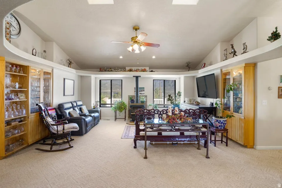 Vaulted ceiling with skylights and a ceiling fan, built-in display cabinetry, and a wood-burning stove with a hearth