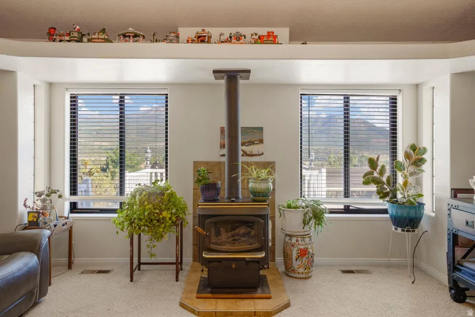Freestanding wood-burning stove with a tile hearth, flanked by two large windows, and a high display shelf