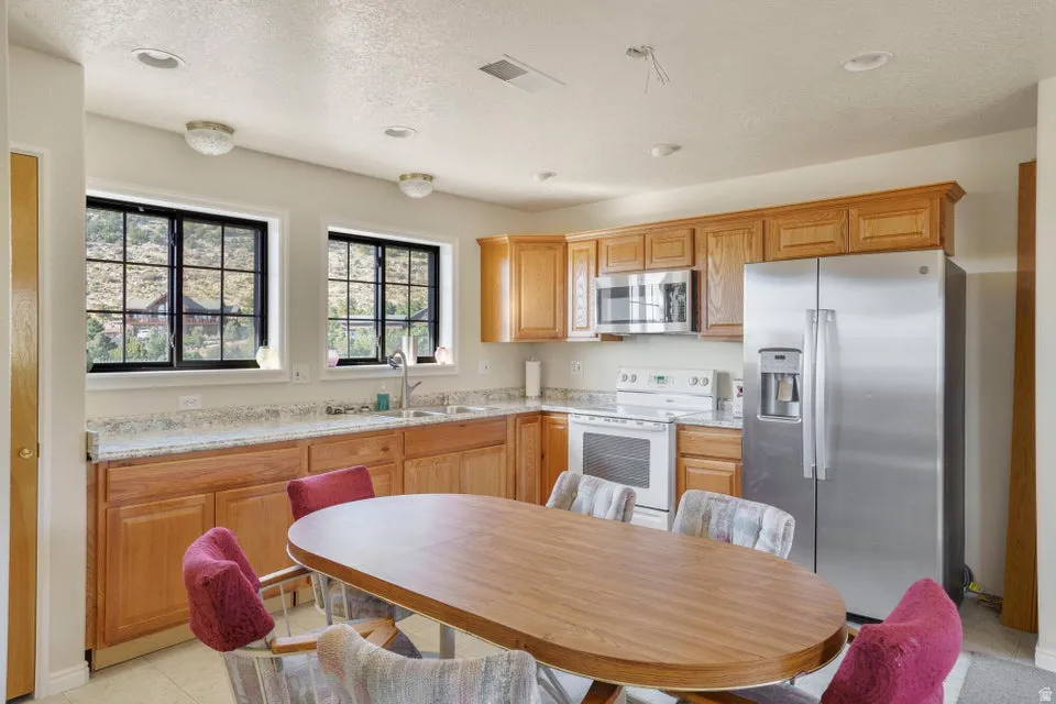 Kitchen featuring wood cabinetry, stainless steel appliances, recessed lighting, and dual windows