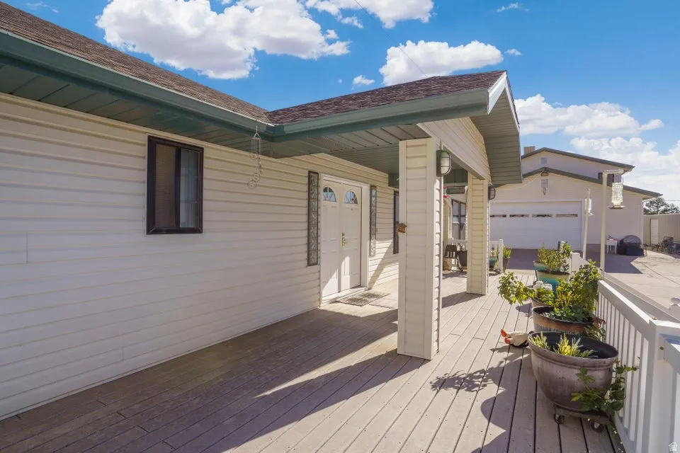 Expansive covered porch with wood-finish decking, white siding exterior, and a two-car garage