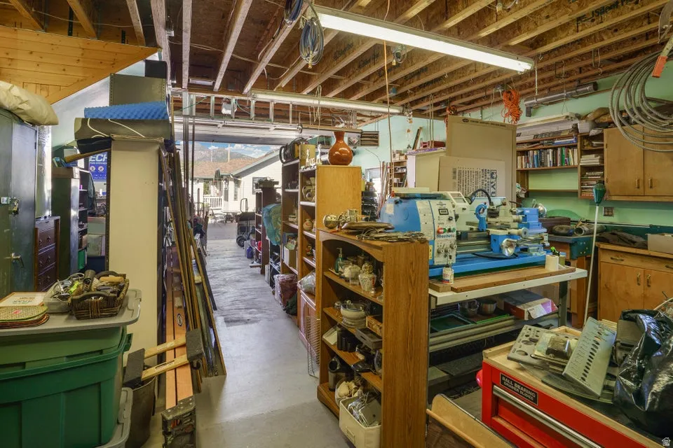 Exposed wood beam ceiling, fluorescent lighting, built-in shelving, wood cabinetry, painted walls