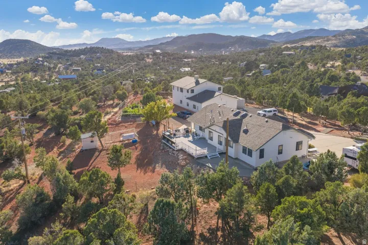 Expansive property with a multi-level deck, surrounding natural landscape, and distant mountain scenery