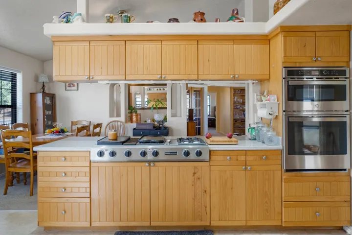 Kitchen featuring extensive light wood cabinetry, stainless steel range with gas burners, stainless steel double wall ovens, and white countertops
