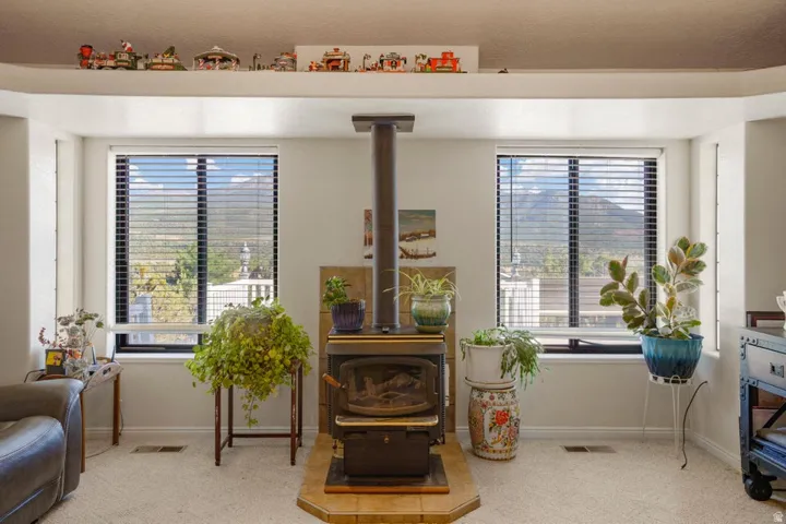 Freestanding wood-burning stove with a tile hearth, flanked by two large windows, and a high display shelf