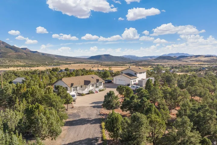 Expansive property featuring two distinct structures, a large driveway, and a natural, verdant landscape with extensive tree coverage