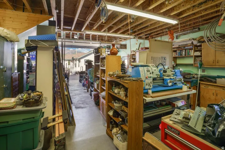 Exposed wood beam ceiling, fluorescent lighting, built-in shelving, wood cabinetry, painted walls