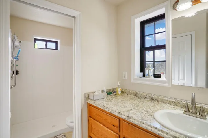 Bathroom featuring a single vanity with a light-toned countertop, an undermount sink, and wood-finish cabinetry