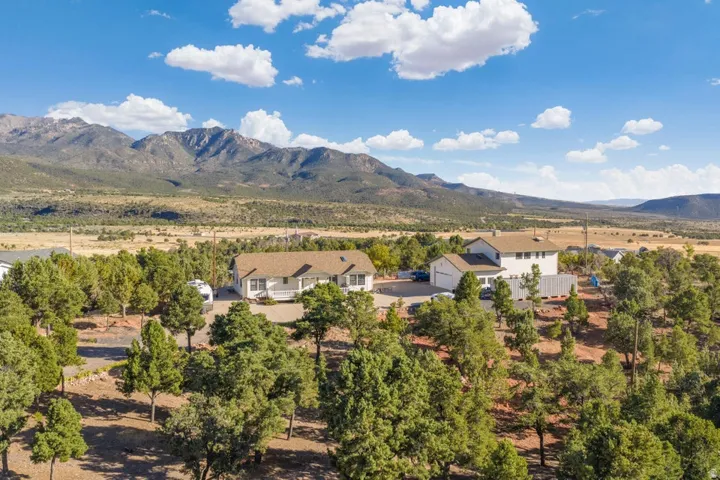 Mountain backdrop, expansive terrain, multiple structures, mature trees, clear sky