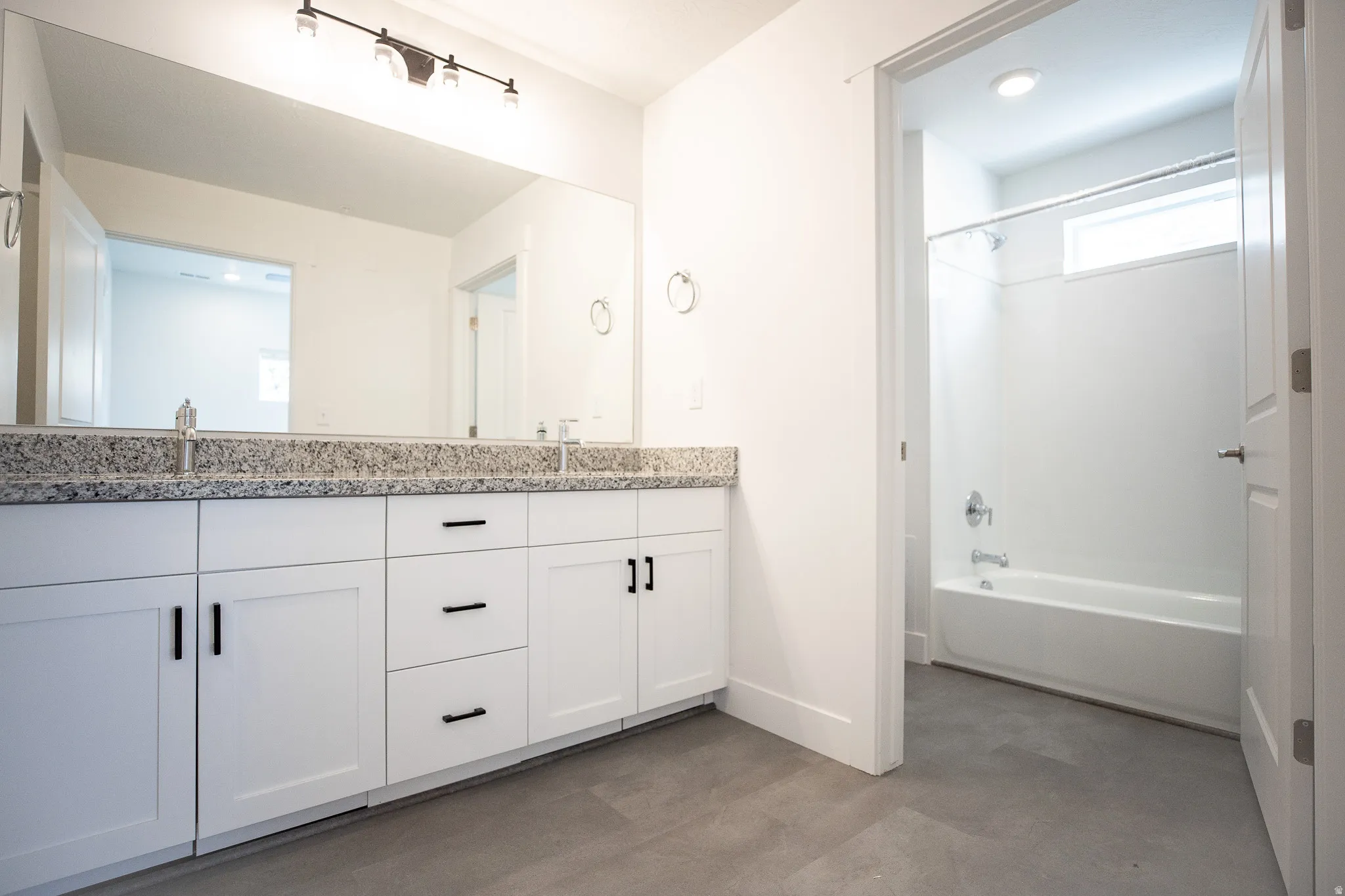 Primary ADA accessible bathroom with grab bars, dual sinks, painted white wood cabinets and granite counters.
