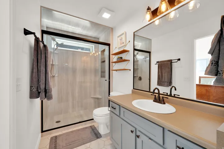 Walk-in shower with clear glass enclosure, tile surround, and transom window