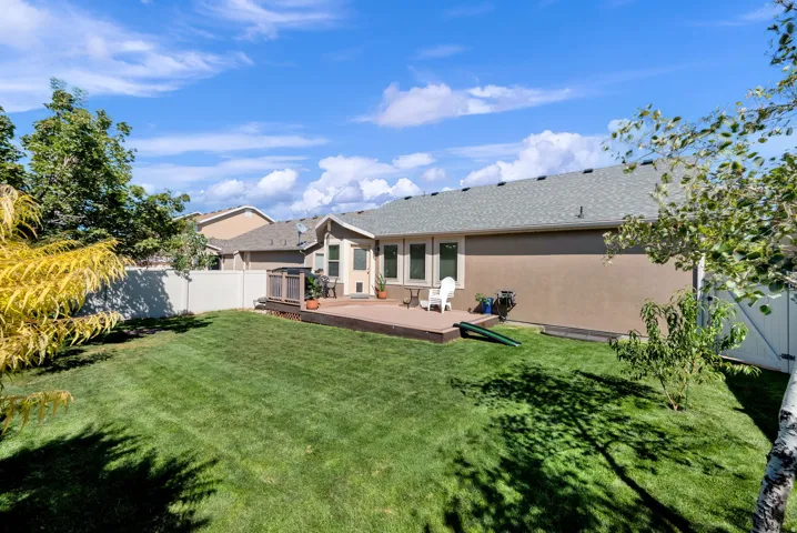 Expansive backyard with a large lawn, wood-tone deck, and privacy fencing
