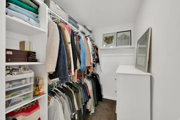 Walk-in closet with integrated shelving, multiple hanging rods, and a built-in dresser