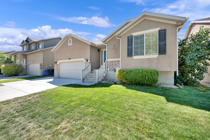 Stucco exterior with brick accents, attached garage, and a concrete driveway
