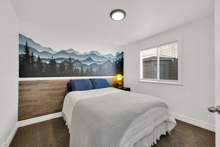 Accent wall featuring a mountain and forest mural, wood-finish paneling, single window with blinds, and flush mount ceiling light
