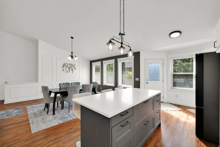 Kitchen island with white countertop, dark cabinetry, and integrated storage