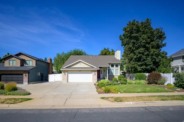 Exterior featuring a two-car garage, concrete driveway, and a white picket fence