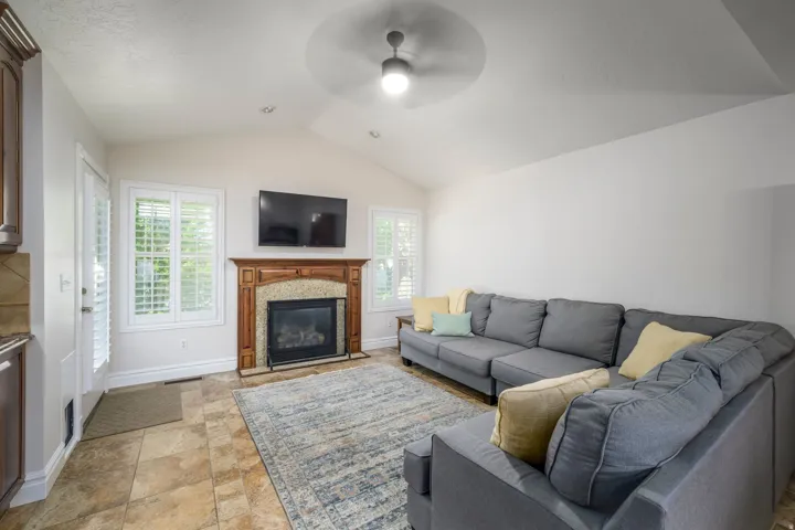 Vaulted ceiling with an attached ceiling fan, recessed lighting, and a fireplace featuring a wood mantel
