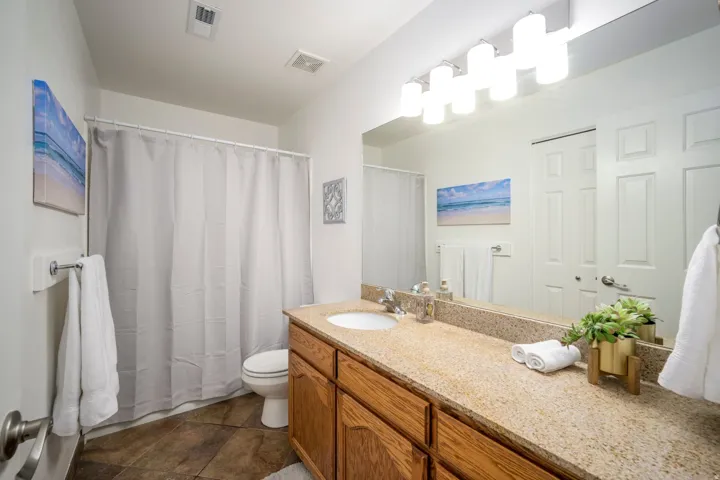 Vanity with a light-colored speckled countertop, undermount sink, and wood-finish cabinetry