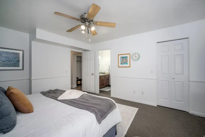 Ceiling fan with integrated lighting, white paneled doors, half-wall wainscoting, and carpeted flooring