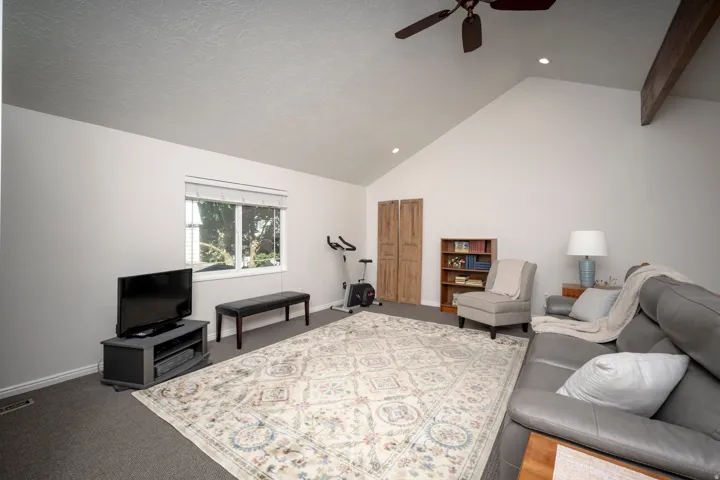 Vaulted ceiling with exposed wood beam, recessed lighting, and ceiling fan
