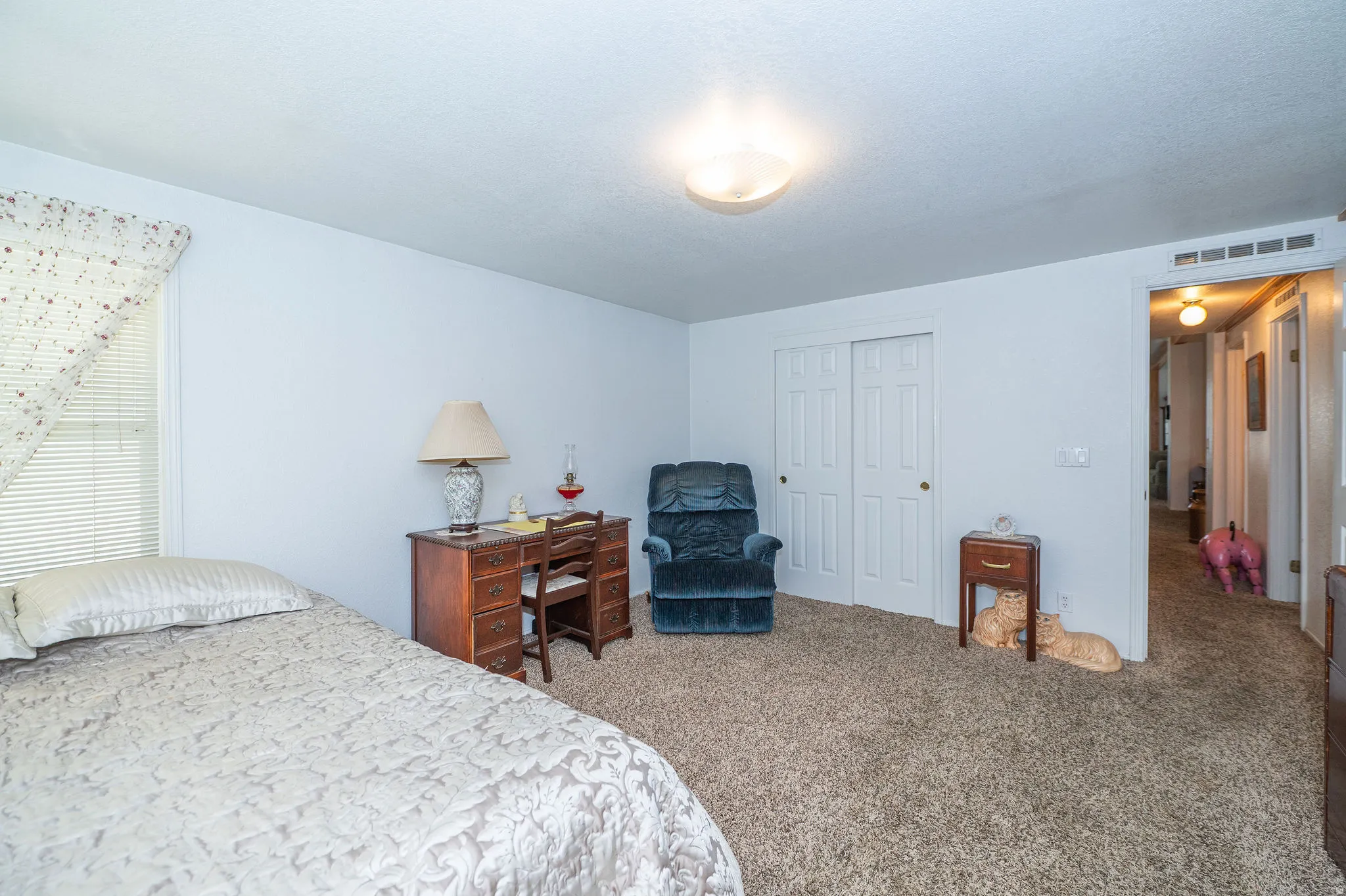 Wall-to-wall carpeting with light-toned walls, featuring a window with blinds, and a built-in closet with sliding doors