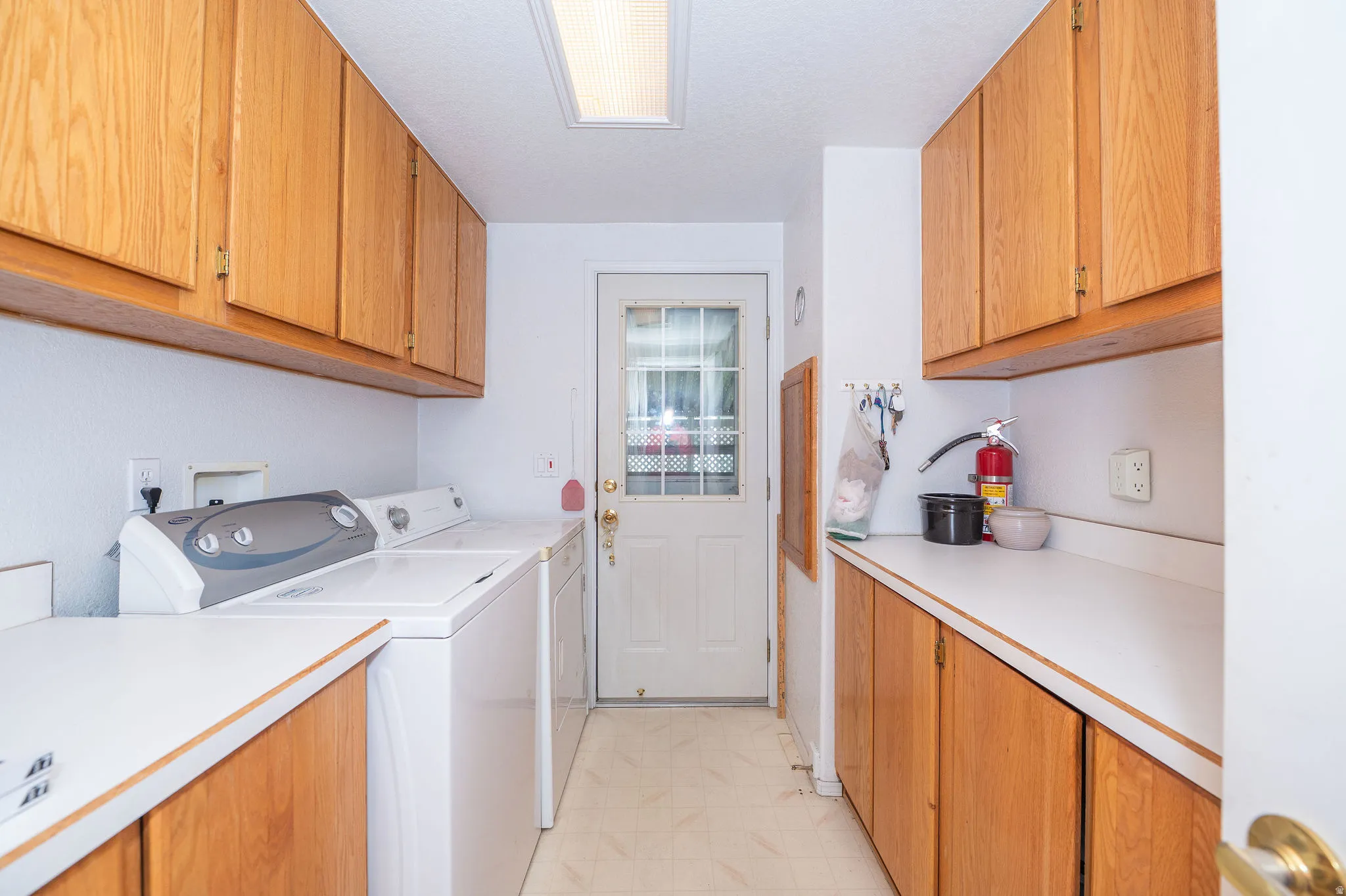 Functional utility area with abundant wood cabinetry, expansive white countertops, and durable flooring