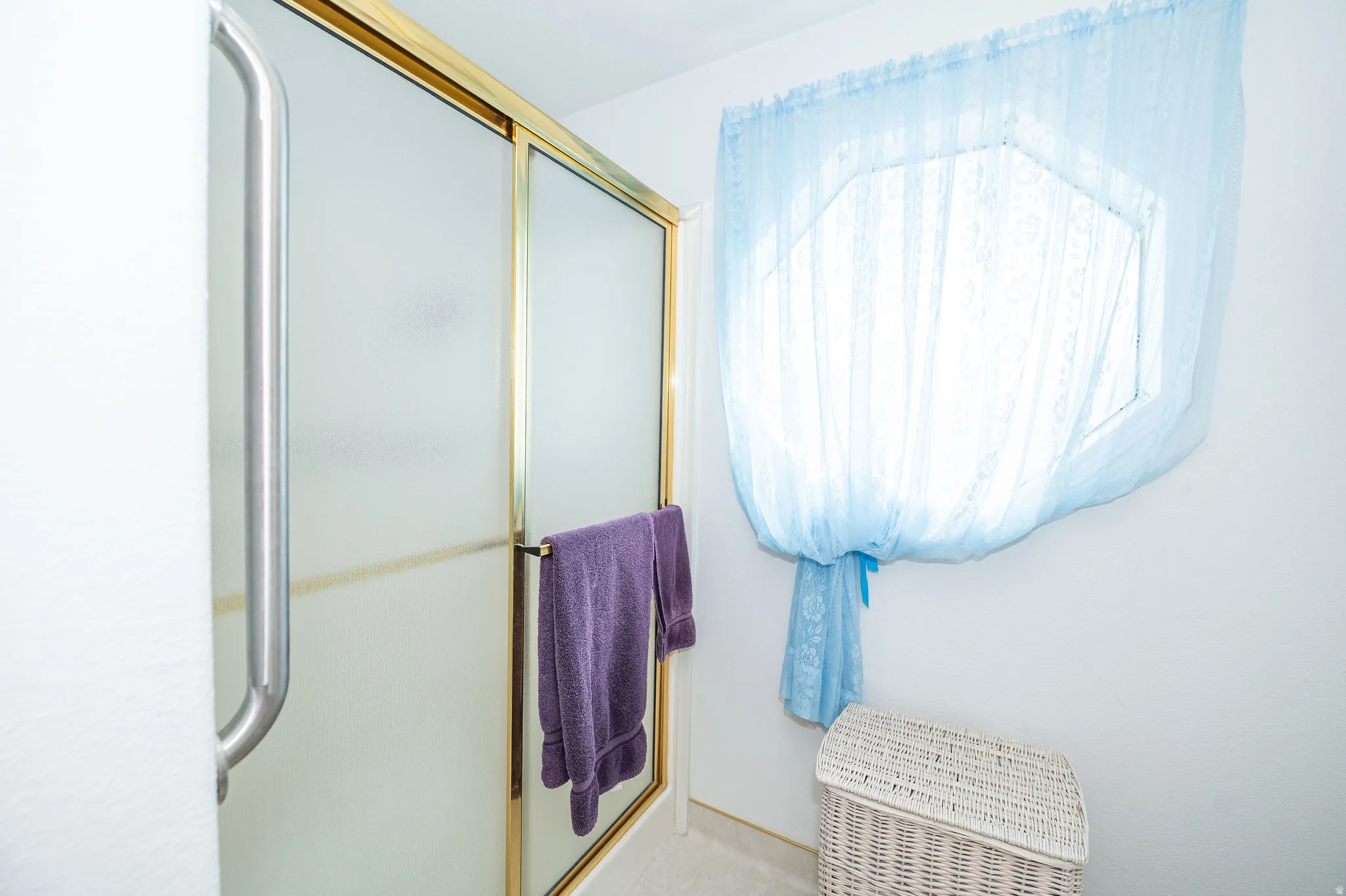 Shower enclosure with frosted glass panels and brass-finish framing