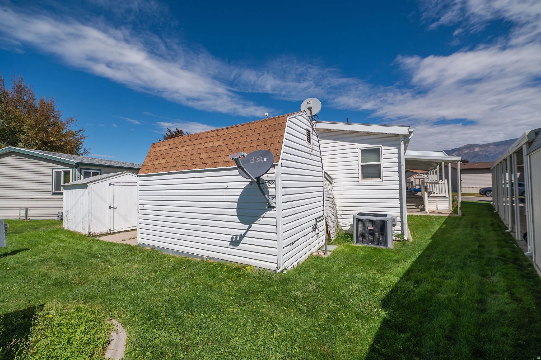 Expansive lawn area featuring a freestanding storage shed with a gambrel roof and an additional smaller storage shed