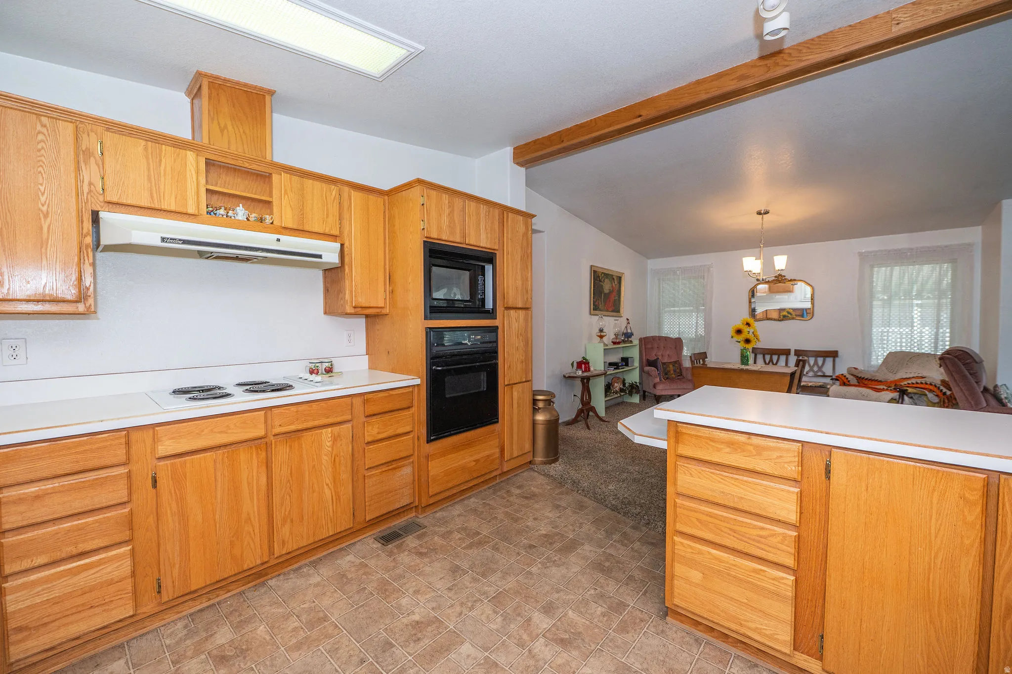 Integrated kitchen and dining area featuring wood cabinetry, white countertops, and a built-in oven and microwave