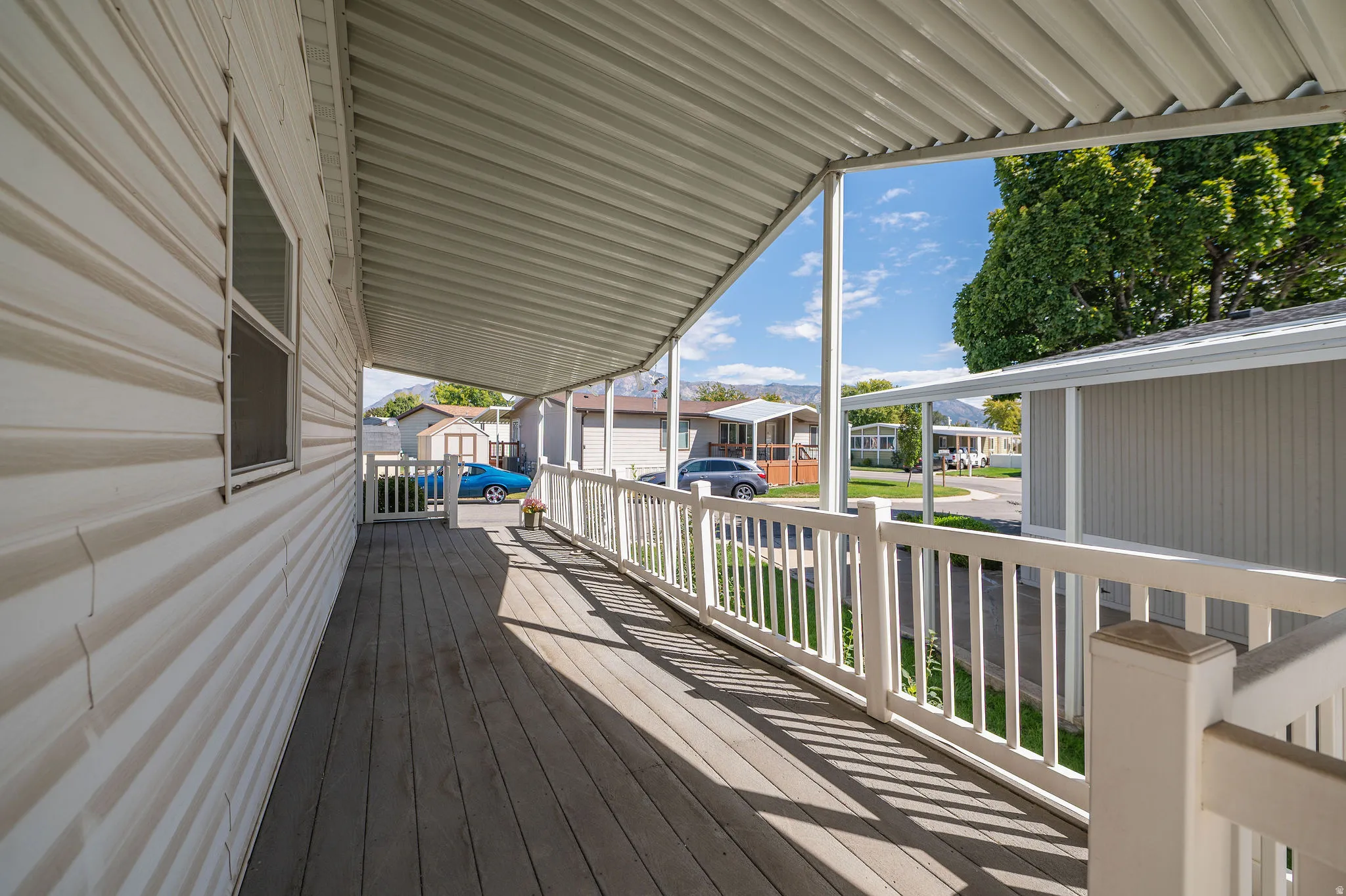 Expansive covered porch featuring finish decking, white railings, and a horizontal siding exterior